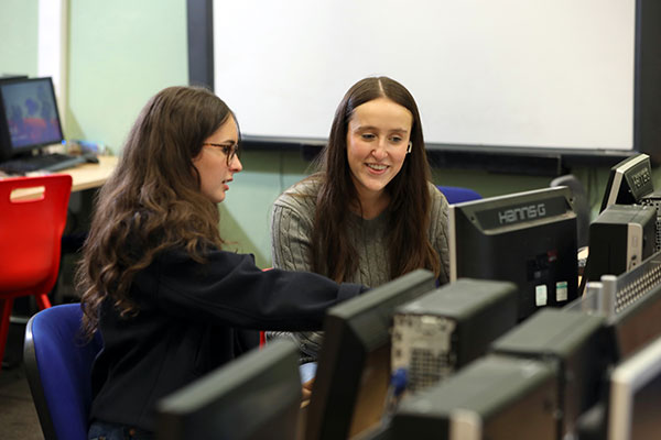 Student using computer with teacher